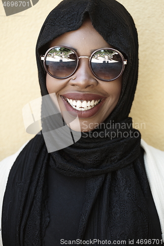 Image of african woman using smartphone wearing traditional islamic clothes
