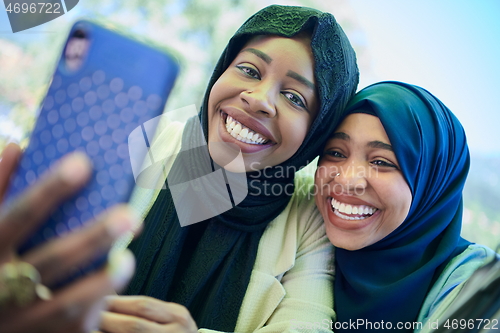 Image of african female friends using smart phone together