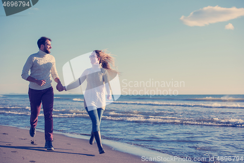 Image of Loving young couple on a beach at autumn sunny day