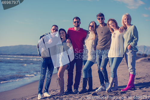 Image of portrait of friends having fun on beach during autumn day