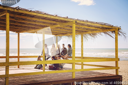 Image of Group of friends having fun on autumn day at beach