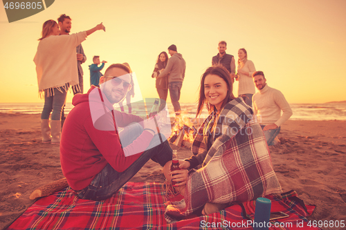 Image of Couple enjoying with friends at sunset on the beach