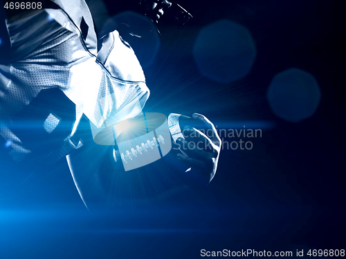 Image of American football player holding ball while running on field