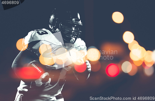 Image of American football player holding ball while running on field