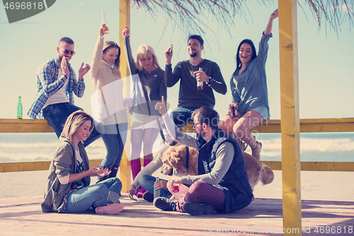 Image of Group of friends having fun on autumn day at beach