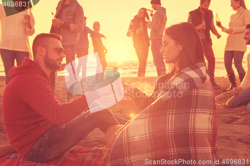 Image of Couple enjoying with friends at sunset on the beach