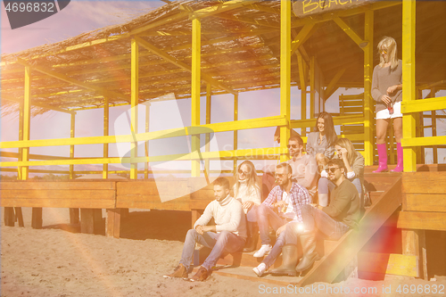 Image of Group of friends having fun on autumn day at beach