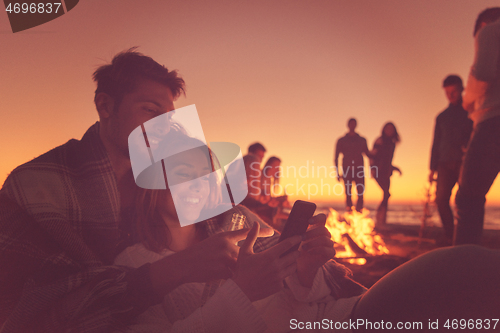 Image of Couple enjoying bonfire with friends on beach