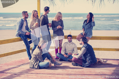 Image of Group of friends having fun on autumn day at beach