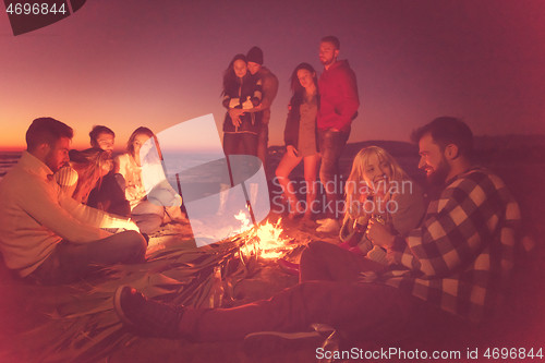 Image of Couple enjoying with friends at sunset on the beach