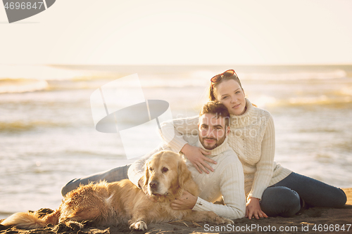 Image of Couple with dog enjoying time on beach