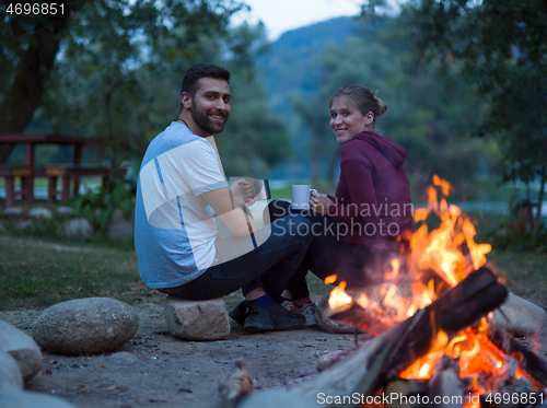 Image of couple sitting around the campfire at evening