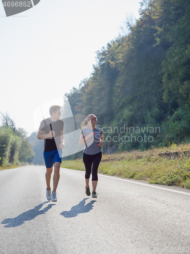 Image of young couple jogging along a country road