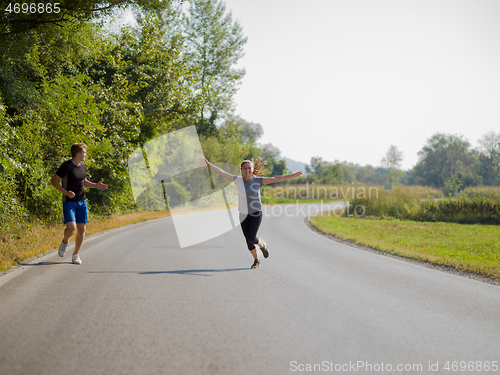 Image of young couple jogging along a country road