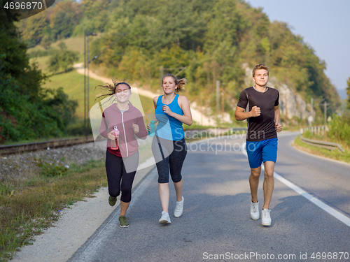 Image of young people jogging on country road