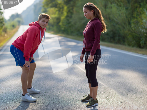 Image of young couple warming up and stretching on a country road