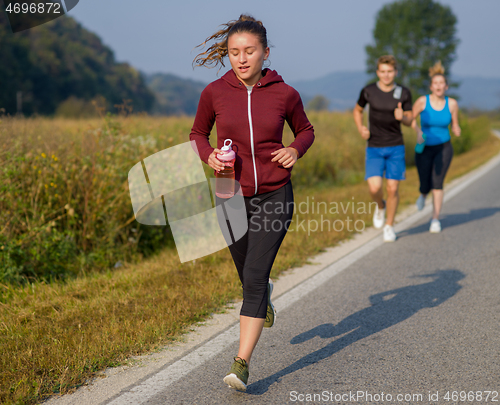 Image of young people jogging on country road