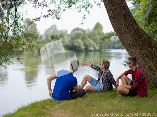 Image of men sitting on the bank of the river