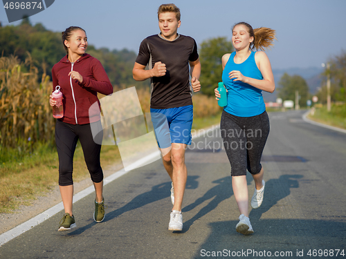 Image of young people jogging on country road