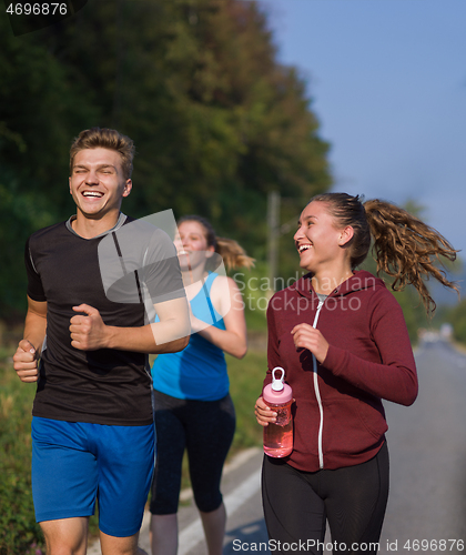 Image of young people jogging on country road