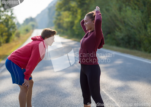 Image of young couple warming up and stretching on a country road