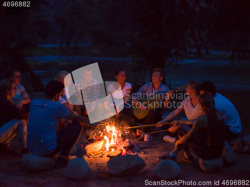 Image of young friends relaxing around campfire