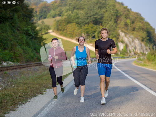 Image of young people jogging on country road