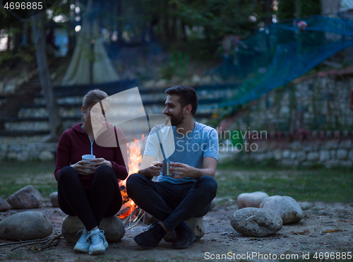 Image of couple sitting around the campfire at evening