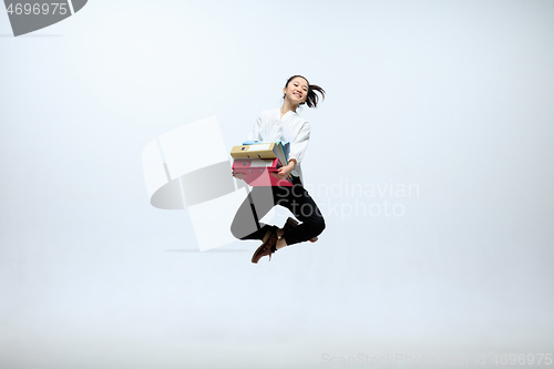 Image of Woman working at office and jumping isolated on studio background