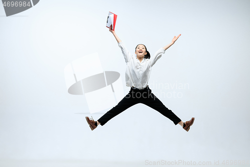 Image of Woman working at office and jumping isolated on studio background