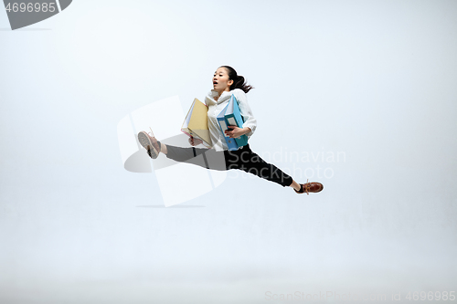 Image of Woman working at office and jumping isolated on studio background