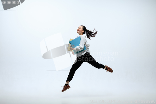 Image of Woman working at office and jumping isolated on studio background