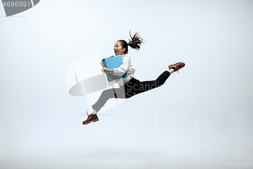 Image of Woman working at office and jumping isolated on studio background