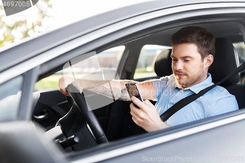 Image of man driving car and using smartphone