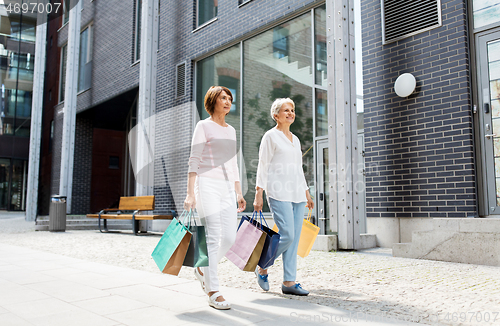 Image of senior women with shopping bags walking in city