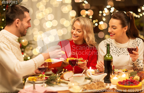 Image of happy friends having christmas dinner at home