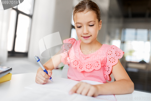 Image of student girl with book writing to notebook at home