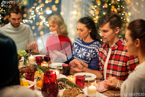 Image of friends having home christmas dinner and praying