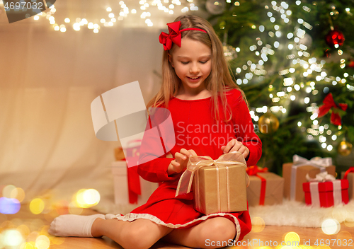 Image of smiling girl with christmas gift at home