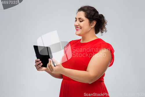 Image of happy woman in red dress using tablet computer
