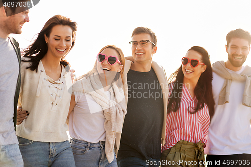 Image of happy friends walking along summer beach