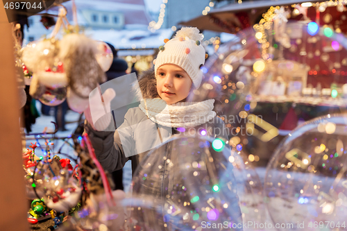 Image of little girl choosing christmas balls at market