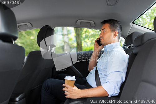 Image of businessman with coffee calling on phone in car