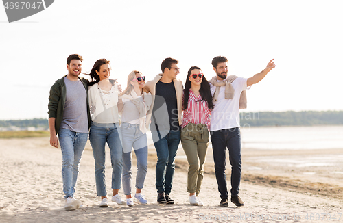 Image of happy friends walking along summer beach