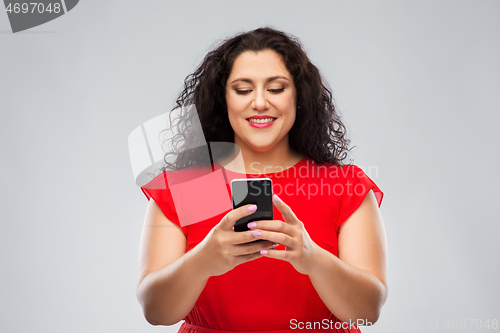 Image of happy woman in red dress using smartphone