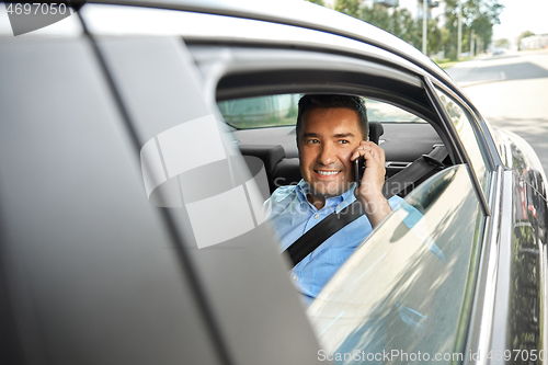 Image of male passenger calling on smartphone in taxi car