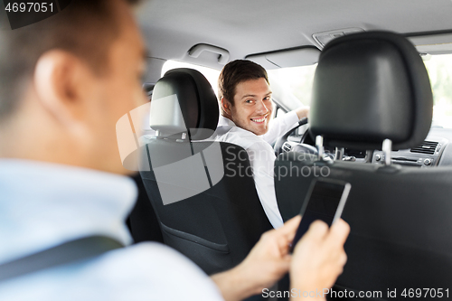 Image of male car driver and passenger with smartphone