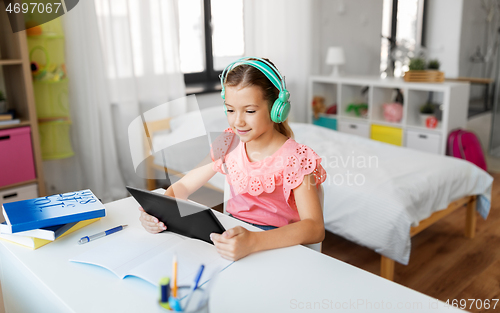 Image of girl in headphones with tablet computer at home