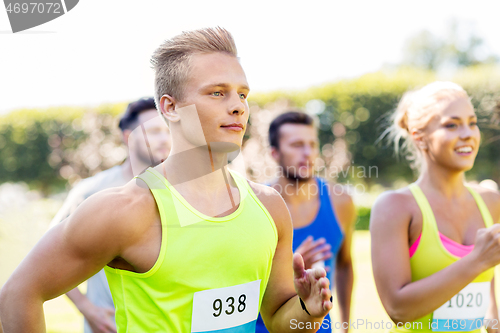 Image of happy young sportsmen racing wit badge numbers