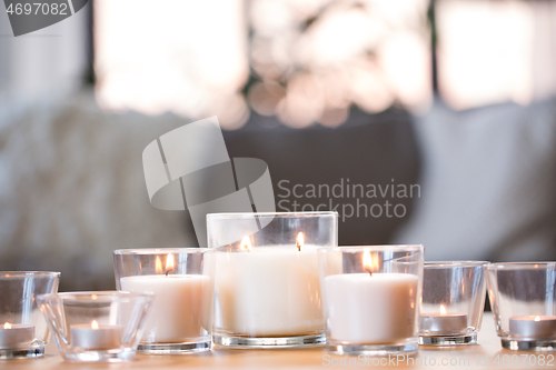 Image of burning white fragrance candles on table at home